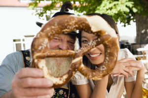 Deutschland,Bayern,Oberbayern,Bayerischer Mann und asiatische Frau mit Brezel,Porträt,Nahaufnahme